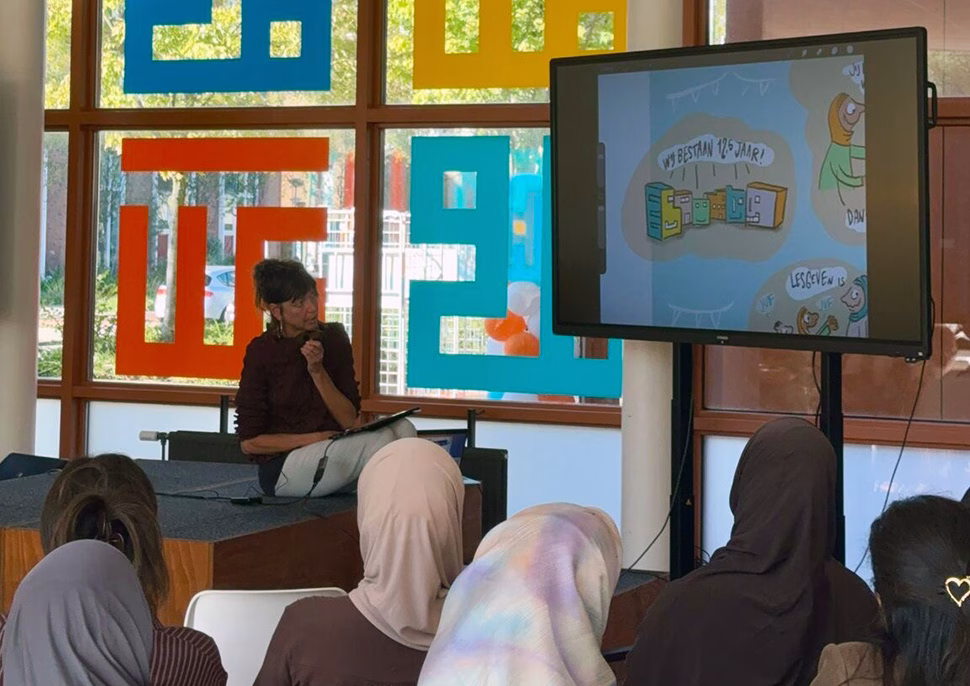 Cunera Joosten presenteert haar digitaal getekende cartoons op een groot scherm tijdens de Dag van de Leraar bij Elifscholen.